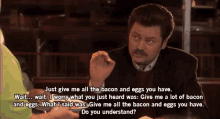 a man with a mustache is sitting at a table and talking to another man
