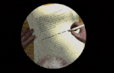 a person is writing on a piece of paper with their name written on the bottom right
