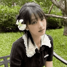 a young woman with a flower in her hair is sitting on a bench .