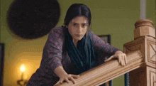 a woman is standing on a set of stairs holding onto a railing .