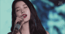 a woman singing into a microphone with the words love poem on the bottom right