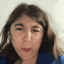 a woman in a blue shirt is making a face