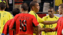 a group of soccer players are shaking hands and one of them has the number 18 on his back
