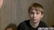 a girl in a blue shirt is holding a black puppy and the website gagfilms.com is visible behind her