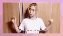 a woman in a white t-shirt is standing in front of a wall with her hands in the air .