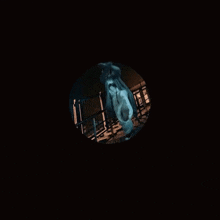 a woman in a hooded sweatshirt with black nails is sitting in a dark room