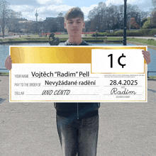 a young man is holding a large check that says your name vojtech radim pell