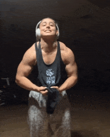 a muscular man wearing headphones and a black tank top that says team on it