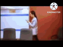 a woman is standing in front of a red wall holding a cell phone in her hand .