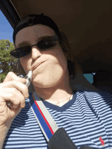 a man wearing sunglasses and a striped shirt is smoking a cigarette