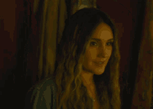 a woman with long hair is smiling in a dark room .