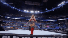 a woman in a wonder woman costume is standing in the middle of a wrestling ring ..