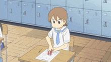 a girl is sitting at a desk with a red box on it