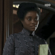 a woman is smiling and holding a book with the hbo logo behind her