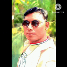 a man wearing sunglasses and a white shirt with the letter k on the bottom