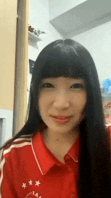 a woman with long black hair is wearing a red shirt with stars on it and smiling .