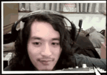 a man with long hair and a beard is wearing headphones .