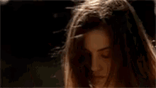 a close up of a woman 's face in a dark room with a towel behind her .