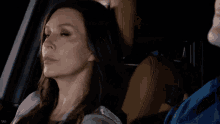 a woman is sitting in the back seat of a car with a man behind her
