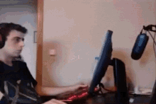 a man wearing headphones sits in front of a computer monitor and microphone