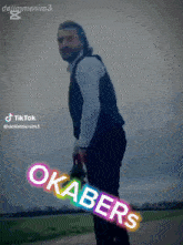 a man with a beard is holding a rainbow colored sign that says okabers on it