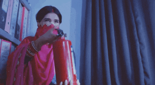 a woman in a pink dress holds a fire extinguisher