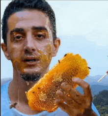 a man with honey on his face is holding a piece of honeycomb