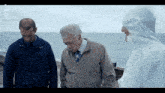 a man in a white suit stands next to two men