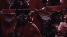 a group of gremlins are sitting in a theatre eating popcorn .