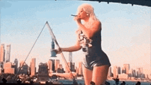 a woman is singing into a microphone on a stage with a city in the background .