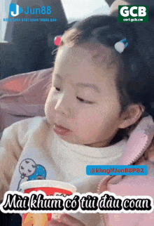 a little girl holding a cup with a gcb logo on the bottom right