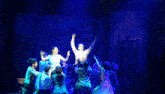 a group of people are dancing on a stage and one of them is wearing a shirt that says ' reebok ' on it