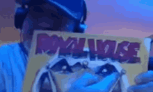 a man wearing headphones is holding a piece of paper that says `` royal noise '' .