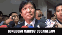 a man in a suit and tie is surrounded by microphones with the words bongbong marcos ' cocaine jaw below him