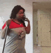 a woman is holding a mop and talking on a cell phone .
