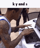 a man with tattoos is typing on a keyboard with the words " k y and s " above him