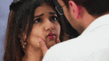 a man is touching a woman 's face and making a funny face .