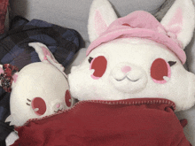 a white stuffed animal with red eyes and a pink hat