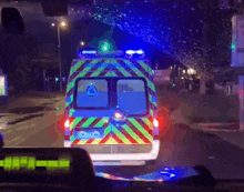 an ambulance is driving down a street at night with blue lights on