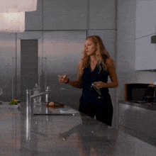 a woman is standing in a kitchen holding a martini glass