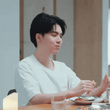 a man is sitting at a table with a plate of food and a glass of water in front of him