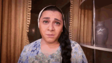 a woman with long hair and a head scarf is making a sad face .