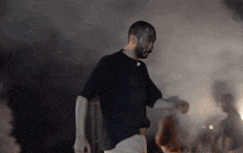 a man with a beard is dancing in a dark room with smoke coming out of the ceiling .