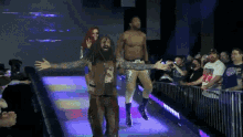 a wrestler with his arms outstretched walks down a ramp