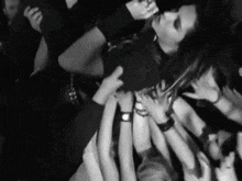 a black and white photo of a crowd of people holding a woman