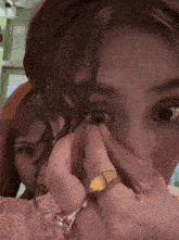 a woman with a yellow ring on her finger is putting a contact lens in her eye