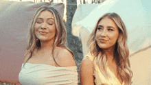 two women are standing next to each other and one is wearing a white top