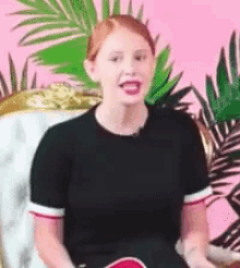a woman is sitting in a chair with a palm tree in the background and smiling .