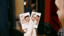 a person is holding two pictures of a man and a woman