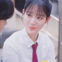 a woman wearing a white shirt and purple tie looks at the camera